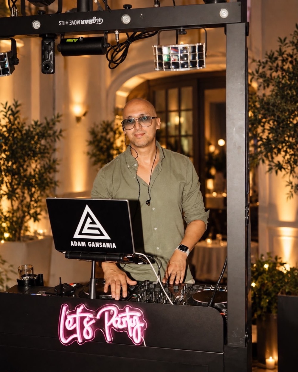 DJ Adam Gansania hinter seinem beleuchteten DJ-Booth mit „Let's Party