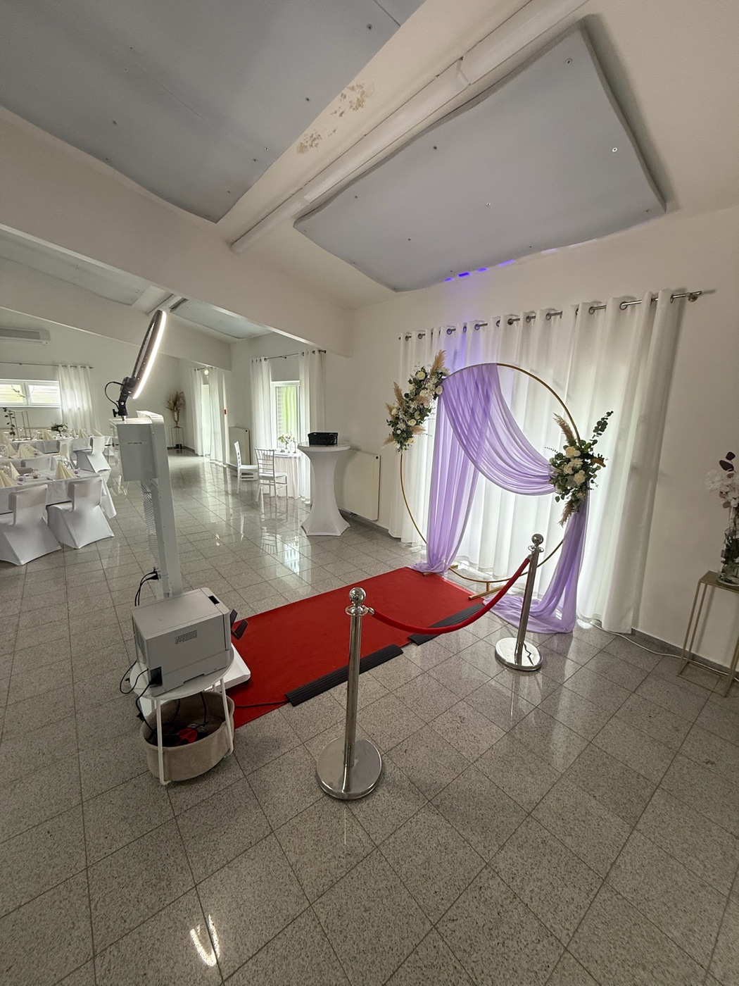 Fotobox vor eleganter Location mit Blumenbogen und lila Deko