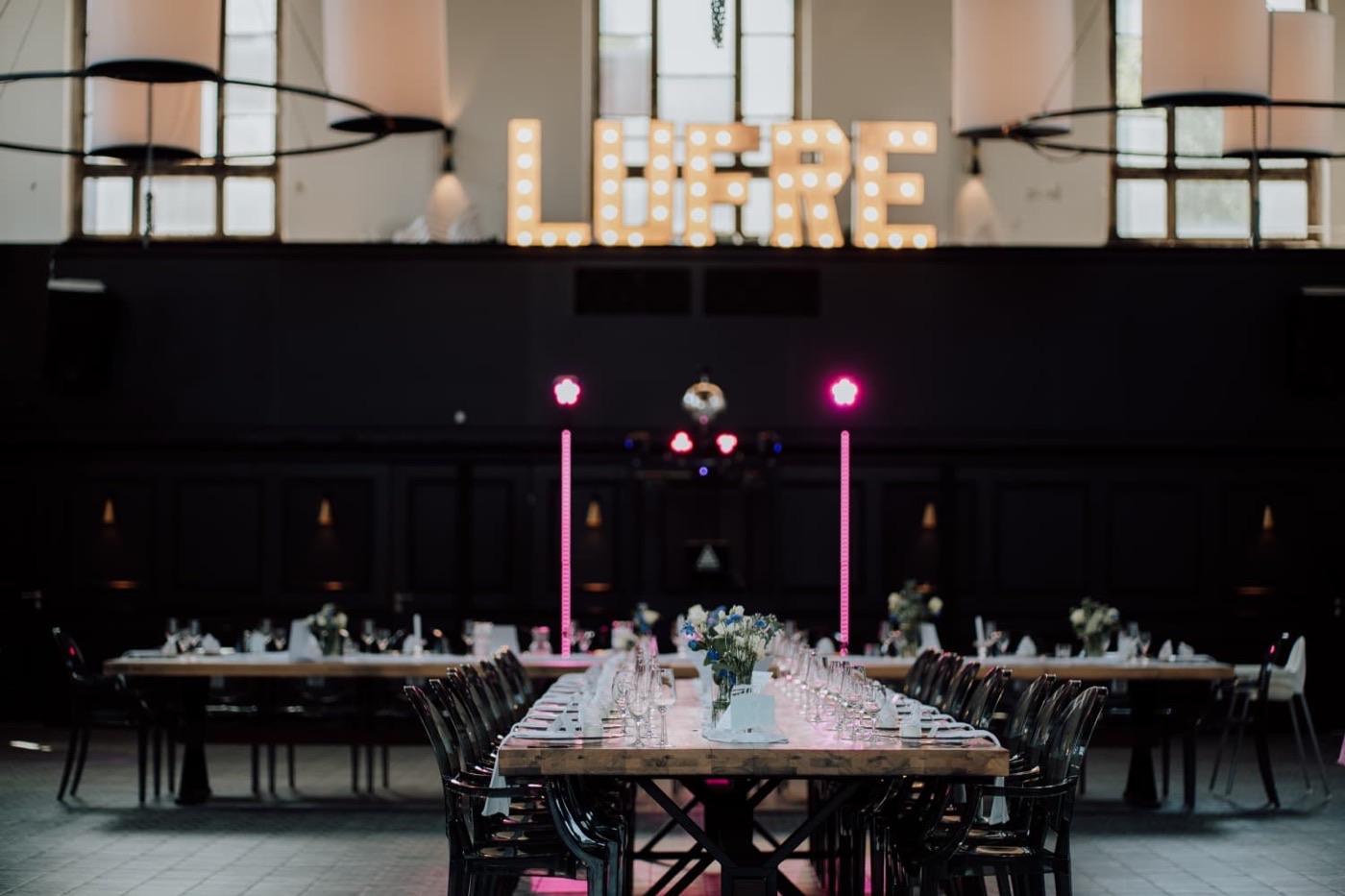 Festlich eingedeckte Tafeln in der Eventhalle mit LUMIÈRE-Leuchtbuchstaben