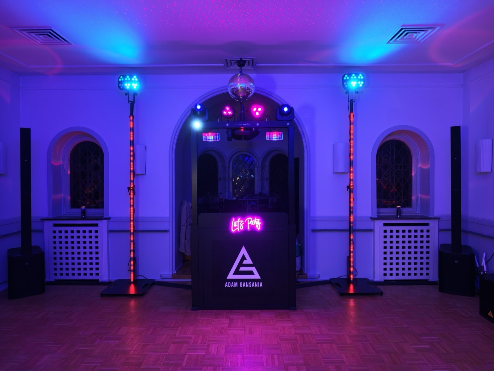 Adam Gansanias DJ-Booth im violetten Licht mit Discokugel und „Let's Party